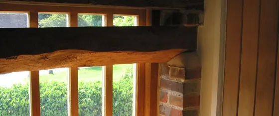 A new oak lintel over a timber-framed window, set into an old brick wall