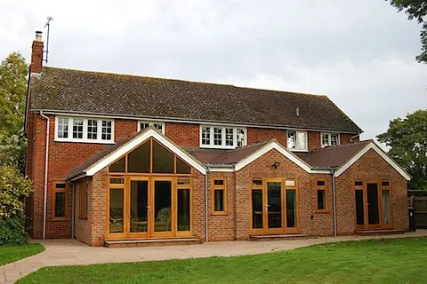 A brick house with a rear extension of glazed gables opening onto the lawn